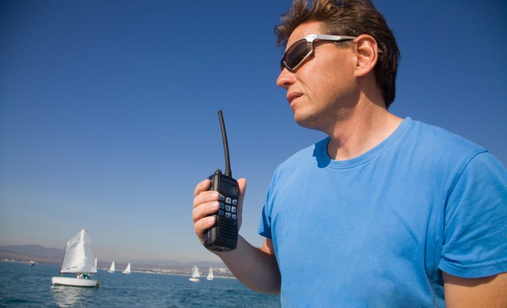 some man with walkie-talkie on the background of the sea with sails